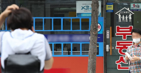 한 시민이 부동산공인중개업소 매물정보 게시판 앞에서 전화통화를 하고 있다. <연합뉴스>